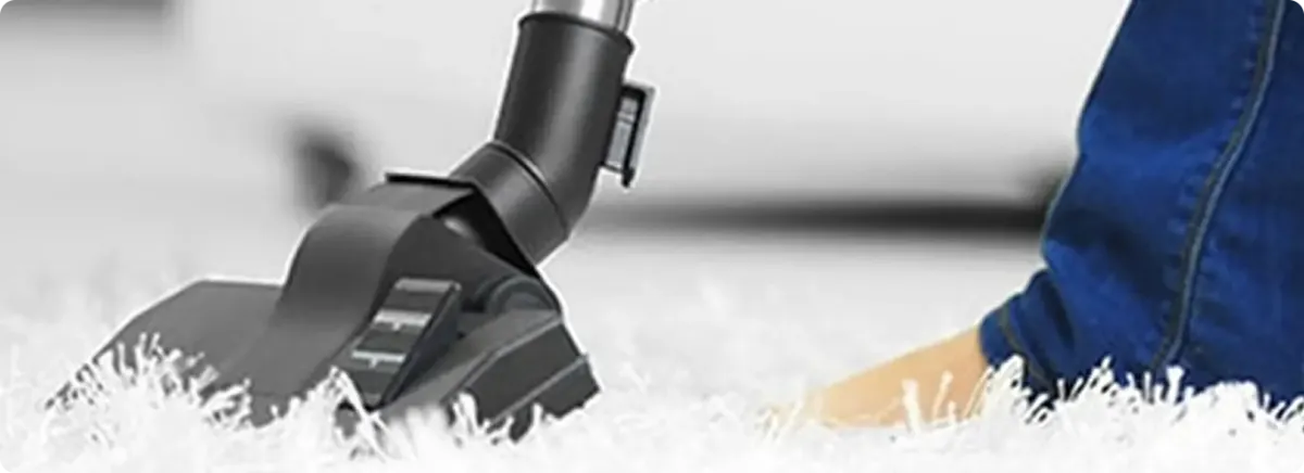 Close-up of a professional vacuuming a white carpet in Roxbury Crossing.